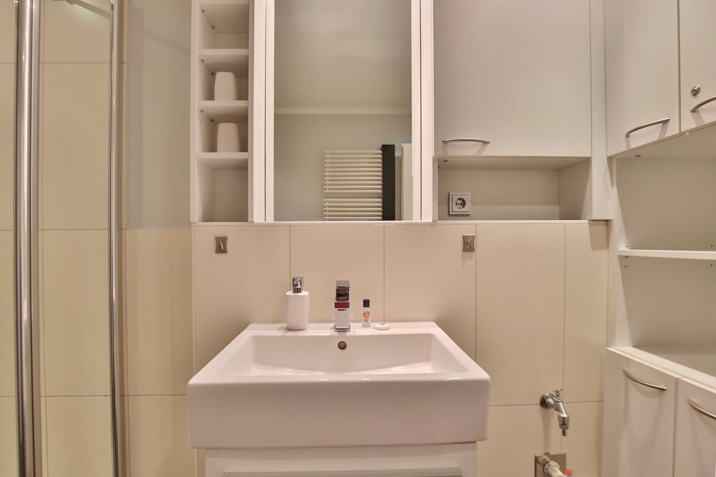 Ein Badezimmer mit Waschbecken, Spiegel und Stauraumschränken.