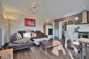 Un salon moderne comprenant un canapé, une table basse et un coin repas avec une table et des chaises. Il y a également une cuisine équipée d’une cuisinière et d’un four à micro-ondes.