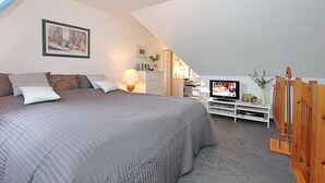 A bedroom with a large bed, a television, a desk, and a wooden gate.
