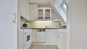 Una cocina compacta con armarios blancos, horno integrado y lavavajillas.