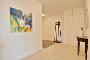 A room with a painting, a coat stand, a wardrobe, and a small table. - Villa Mér Baltique Appartement 10 - Villa Mér Baltique (Timmendorfer Strand)