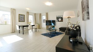 Ein modernes Wohnzimmer mit Essbereich, Flachbildfernseher und einer Couch.