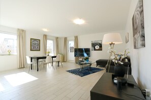 Ein modernes Wohnzimmer mit Essbereich, Flachbildfernseher und einer Couch.