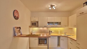 Una cocina moderna con armarios blancos, un microondas, un tostador, un hervidor y un lavabo.