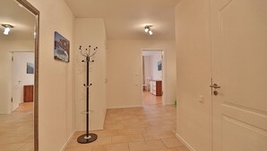 Un pasillo con un perchero, una puerta y vista hacia un cuarto con comedor.