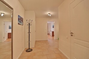 A hallway with a coat rack, a door, and a view into a room with a dining area. - Villa Mér Baltique Appartement 20 - Villa Mér Baltique (Timmendorfer Strand)