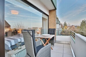Ein Balkon mit Korbmöbeln, einem Tisch und Blick auf die Stadt.