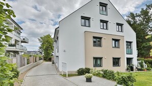 A modern two-story residential building with a flat roof and a mix of window styles.