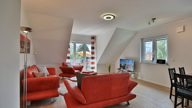 A modern living room with a red sofa set, a dining table, and a TV.