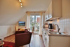 Une cuisine compacte avec un coin repas, un téléviseur et une vue à travers la porte vitrée.