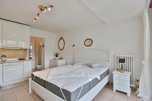 A bedroom with a bed, bedside tables, a nightstand, a mirror, and a radiator.