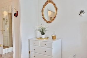 A bathroom with a white vanity, a gold-framed mirror, a potted plant, and a decorative vase.