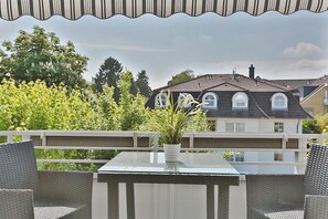 A balcony with wicker furniture, a small table, and a potted plant.