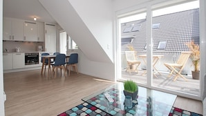 Un apartamento moderno con cocina, comedor y balcón con mobiliario exterior.