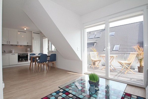A modern apartment with a kitchen, dining area, and a balcony with outdoor seating.