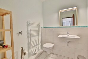 Et badeværelse med toilet, vask og en hvid radiator.