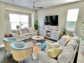 A modern living room with a sofa, chairs, a coffee table, and a TV. - Tran- Quility beach house (Rosemary Beach)