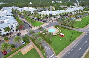 A hotel with a pool, palm trees, and a parking lot. - Tran- Quility beach house (Rosemary Beach)
