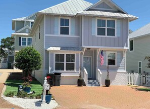 Ein zweistöckiges Haus mit Veranda, kleinem Garten und einer amerikanischen Flagge.