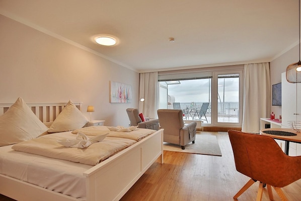 Une chambre d’hôtel moderne équipée d’un lit, d’un bureau, d’une chaise et d’un balcon avec vue.