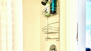 Ein Badezimmer mit Dusche, Handtuchhalter und einer Shampoo-Flasche auf einem Regal.