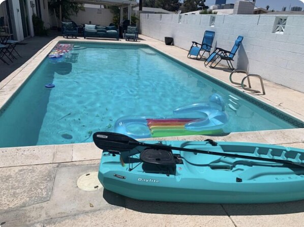A rectangular pool with clear blue water, surrounded by a white wall and a covered patio area with blue lounge chairs. - 🦋Private Master Room with sharedPool Access , Max 2 Guests. (Paradise)