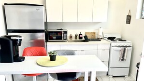 Eine kleine Küche mit Kühlschrank, Mikrowelle, Kaffeemaschine und Herd.