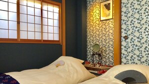 Ein traditionelles japanisches Schlafzimmer mit Tatami-Matten, einem Shoji-Bildschirm und einem Futon-Bett.