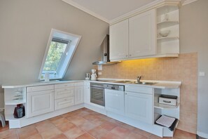 A kitchen with white cabinets, a built-in oven, and a window with a view of greenery.
