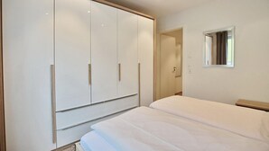 Ein Schlafzimmer mit großem Kleiderschrank, einem Bett und einem Spiegel an der Wand.