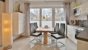 Eine moderne Küche mit Esstisch, Stühlen, einer Mikrowelle und Schränken.