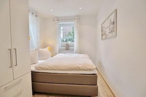 Una camera da letto con un letto, una finestra vista sul verde e un quadro appeso al muro.