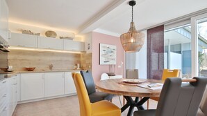 Eine moderne Küche mit weißen Schränken, einer Holzarbeitsplatte und einem Essbereich mit einem runden Holztisch und gelben Stühlen.
