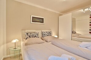 Una camera d'albergo moderna con un letto, un comodino, una lampada e uno specchio.