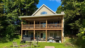 A two-story house with a balcony, outdoor seating, and a grill area.