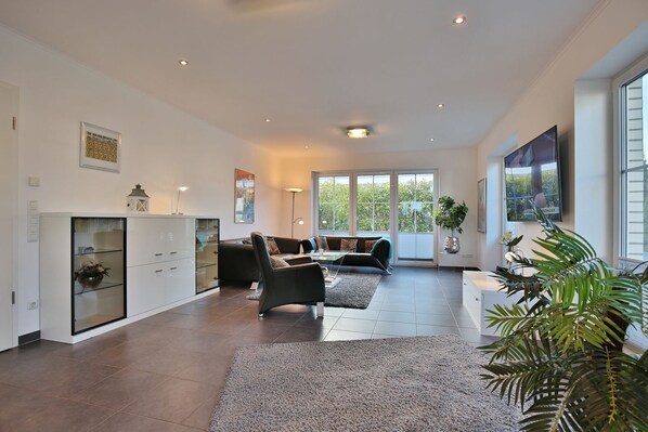 A spacious living area with a sofa set, a coffee table, and a cabinet with glass doors.