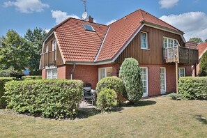 Et toetagers hus med røde tegltage, en parabolantenne og en lille balkon.