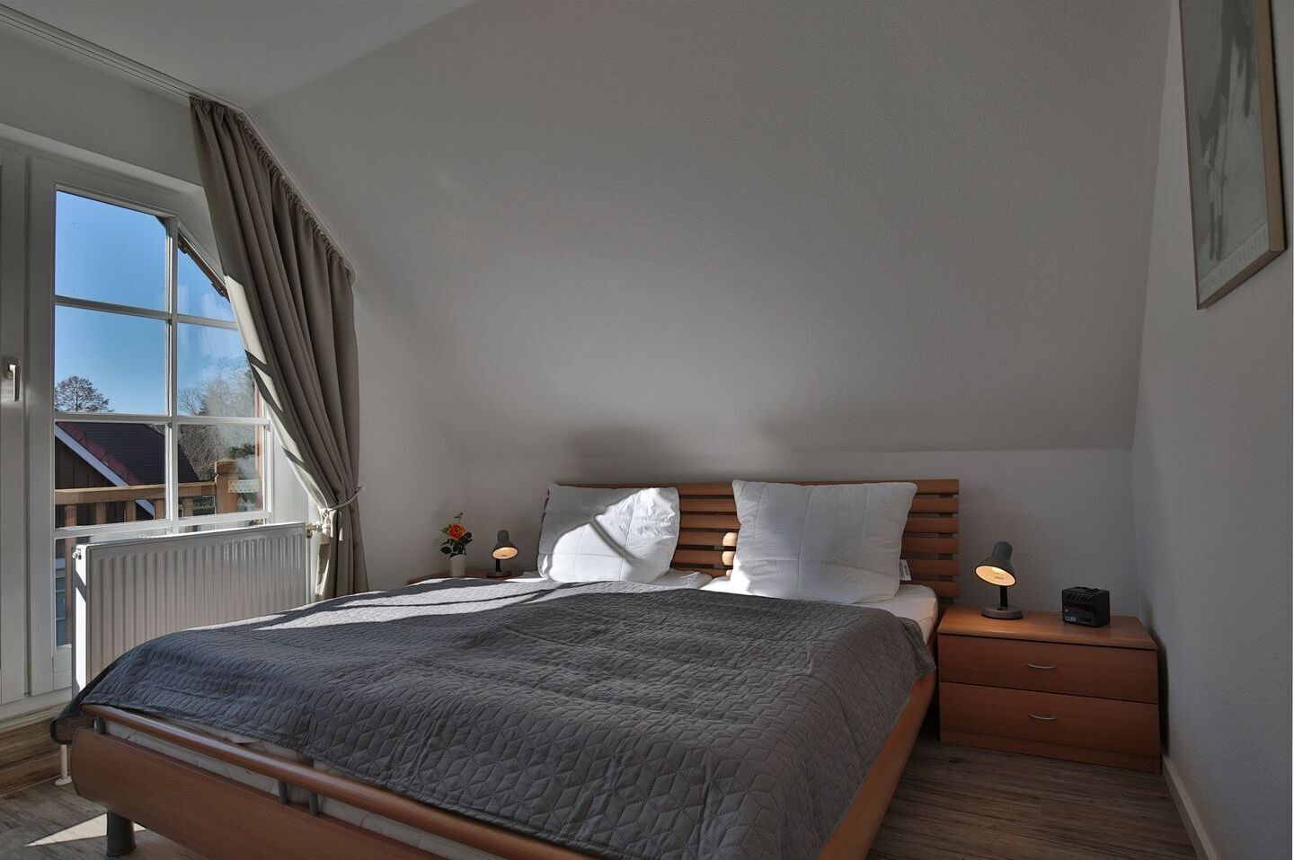 Une chambre à coucher avec un grand lit, une table de chevet avec une lampe et une fenêtre avec des rideaux.