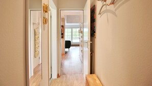 A hallway with a wooden floor, a black chair, and a painting on the wall. - Am Rosenhain 6 Apartment 5 - Am Rosenhain 6 (Timmendorfer Strand)