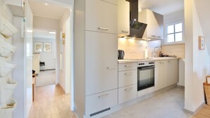A modern kitchen with white cabinetry, a built-in oven, and a window above the sink. - Am Rosenhain 6 Apartment 5 - Am Rosenhain 6 (Timmendorfer Strand)