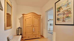 Un couloir avec une armoire en bois, un banc et une œuvre d’art encadrée accrochée au mur.