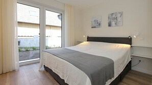 Una camera da letto con un letto, una finestra con tende e due quadri appesi al muro.
