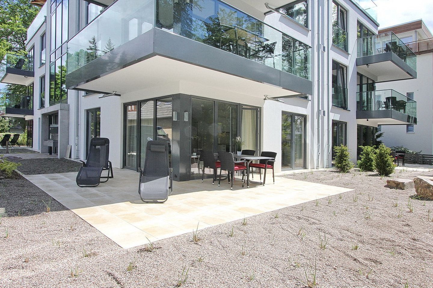 A modern two-story building with a covered patio area featuring outdoor seating.