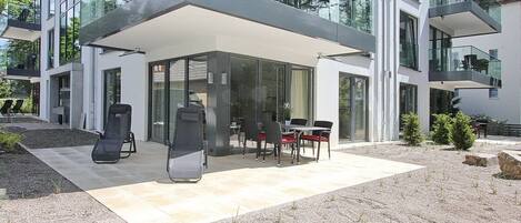 A modern two-story building with a covered patio area featuring outdoor seating.