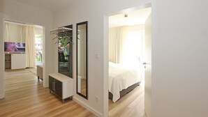 A modern hotel room with a large bed, a TV, a seating area with a plant, and a view of the outdoors. - Villa Stern Apartment 10 - Villa Stern (Timmendorfer Strand)