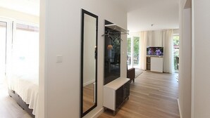 A modern hotel room with a large mirror, a TV, and a balcony with curtains. - Villa Stern Apartment 11 - Villa Stern (Timmendorfer Strand)