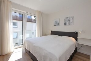Una camera da letto con un letto grande, un balcone vista panoramica e due opere d'arte appese al muro.