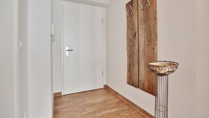 A hallway with a white door, wooden flooring, and a metal floor lamp with a decorative bowl base.