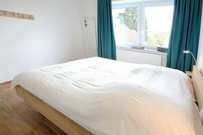 Ein Schlafzimmer mit Bett, einem Fenster mit Vorhängen, einem Heizkörper und einer Stern-Dekoration an der Wand.