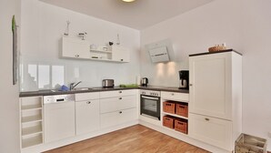 A modern kitchen with white cabinetry, a built-in oven, and a coffee maker.
